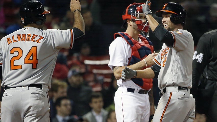 Baltimore Orioles' J.J. Hardy, right, celebrates his two-run home run that also drove in Pedro Alvarez (24) in front of Boston Red Sox's Blake Swihart, behind, during the seventh inning of a baseball game in Boston, Tuesday, April 12, 2016. (AP Photo/Michael Dwyer)